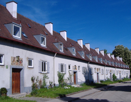 Häusergruppe neben der Pappelallee, im Hintergrund blauer Himmel.